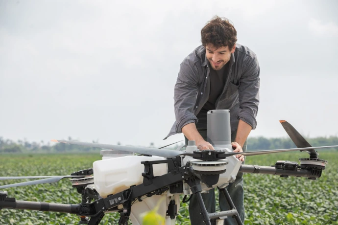 Operador preparando un dron agrícola DJI Agras T55 en un campo de cultivo.
